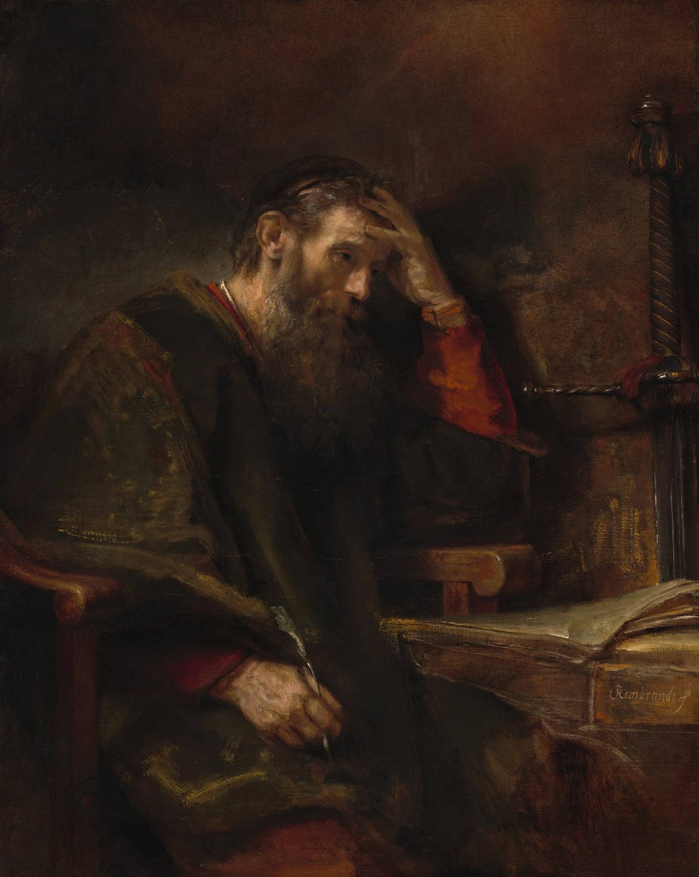 Rembrandt’s painting of a bearded old man in a dark robe seated in a wooden armchair beside a desk, resting his head in one hand and holding a quill in the other, an open book on the desk.